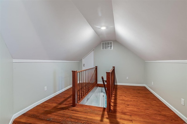 additional living space with lofted ceiling, visible vents, baseboards, and wood finished floors