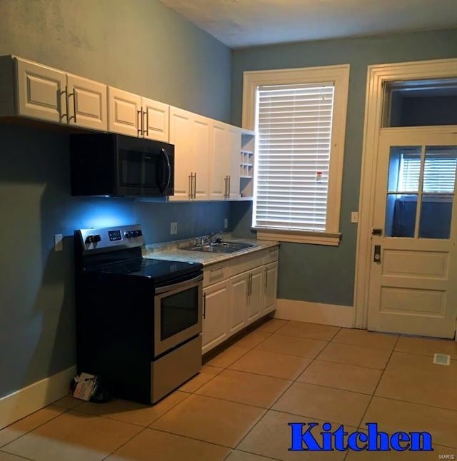 kitchen with sink, stainless steel electric stove, light tile patterned floors, and white cabinetry