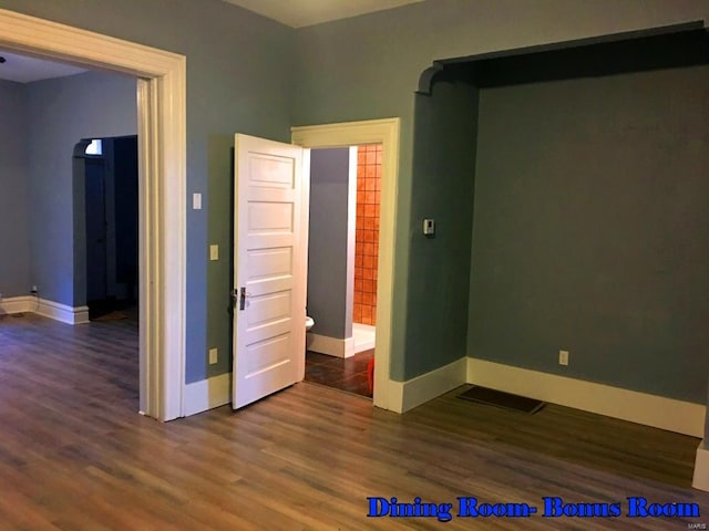 unfurnished bedroom featuring dark hardwood / wood-style floors and ensuite bath