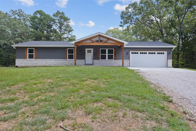 view of front of home featuring stone siding, a front lawn, gravel driveway, and a garage