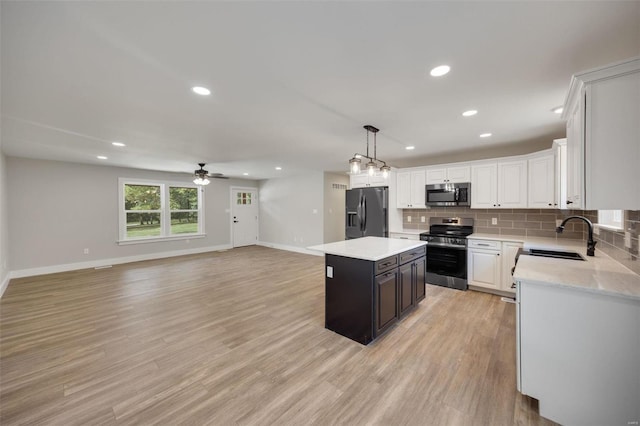 kitchen featuring a kitchen island, sink, ceiling fan, appliances with stainless steel finishes, and light hardwood / wood-style floors