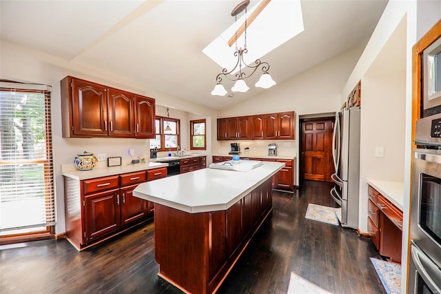 kitchen featuring appliances with stainless steel finishes, a center island, plenty of natural light, dark hardwood / wood-style floors, and decorative light fixtures