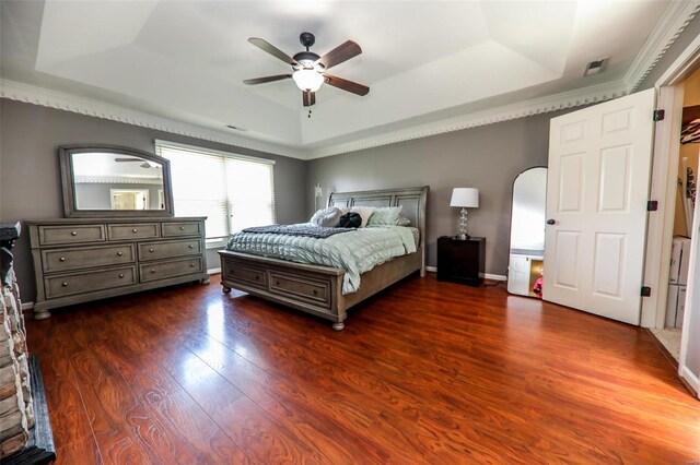 bedroom with a raised ceiling, ceiling fan, and dark hardwood / wood-style flooring