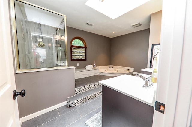 bathroom with vanity, tile patterned flooring, a tile shower, and a skylight