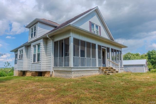 view of side of property with a sunroom and a yard