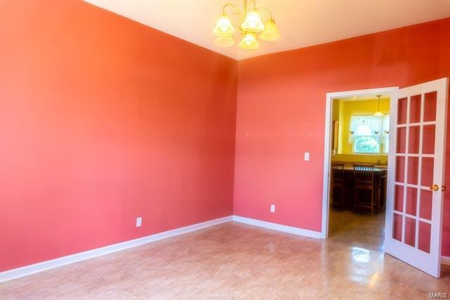 unfurnished room with a chandelier and concrete flooring