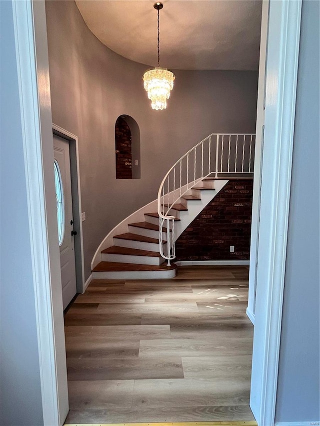 staircase featuring a high ceiling, a chandelier, and wood-type flooring