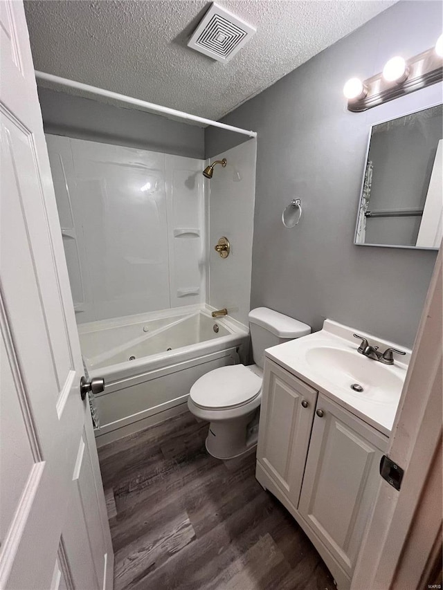 full bathroom featuring hardwood / wood-style flooring, shower / washtub combination, a textured ceiling, vanity, and toilet