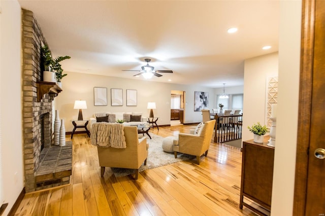 living room with hardwood / wood-style floors, a brick fireplace, and ceiling fan