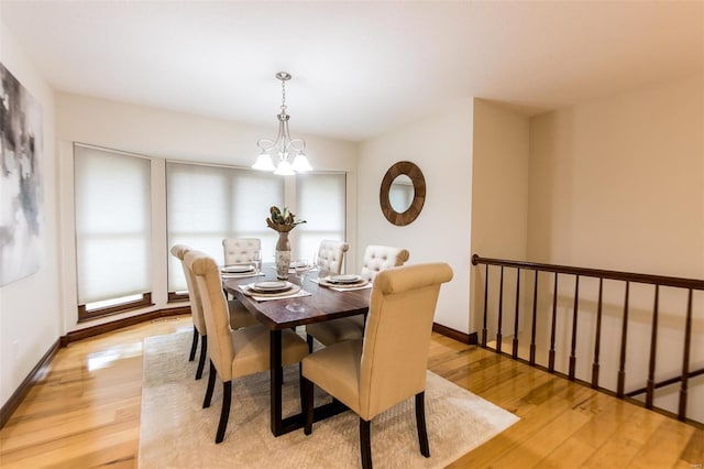 dining space with light hardwood / wood-style floors and an inviting chandelier