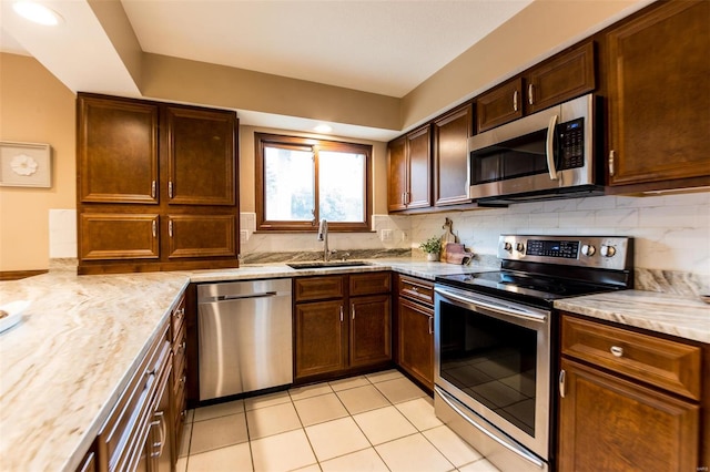 kitchen with tasteful backsplash, light stone counters, light tile patterned floors, sink, and stainless steel appliances