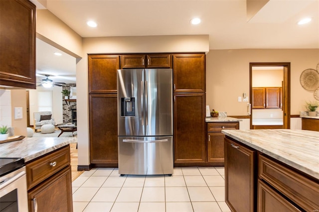 kitchen with light stone countertops, stainless steel fridge with ice dispenser, a fireplace, and light tile patterned floors