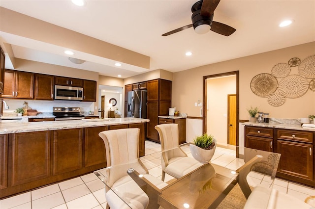 dining room featuring ceiling fan, light tile patterned flooring, and a barn door