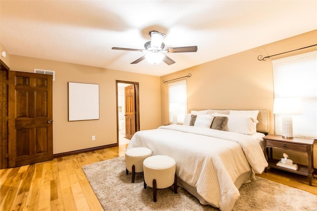 bedroom with multiple windows, ensuite bathroom, light wood-type flooring, and ceiling fan