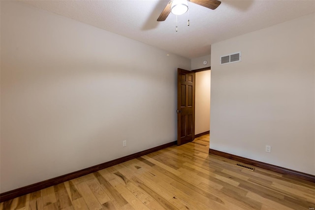 spare room with a textured ceiling, light wood-type flooring, and ceiling fan