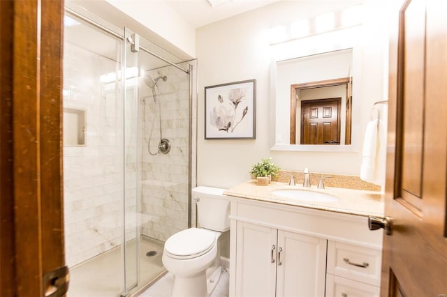 bathroom featuring toilet, vanity, and a shower with door