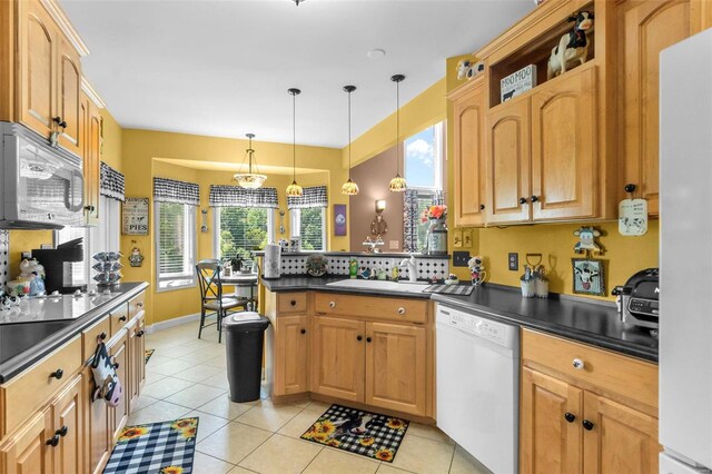 kitchen with sink, decorative light fixtures, kitchen peninsula, light tile patterned flooring, and white appliances