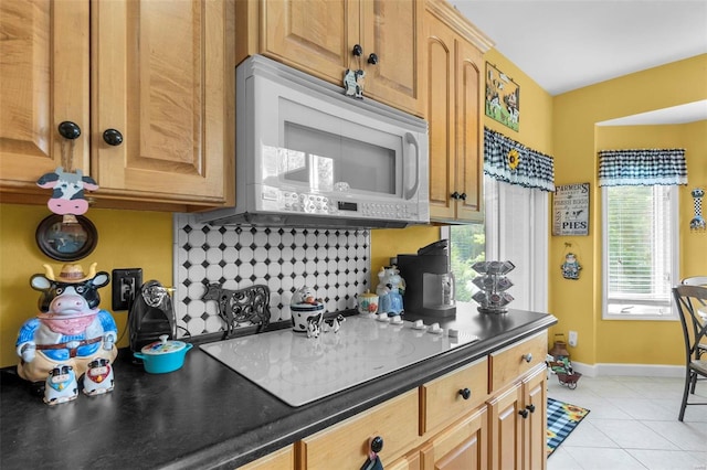 kitchen featuring tasteful backsplash, dark countertops, white microwave, light tile patterned flooring, and baseboards