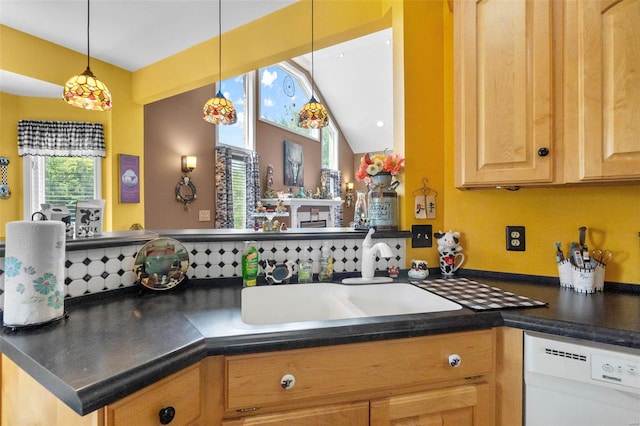 kitchen with dark countertops, lofted ceiling, a peninsula, white dishwasher, and a sink