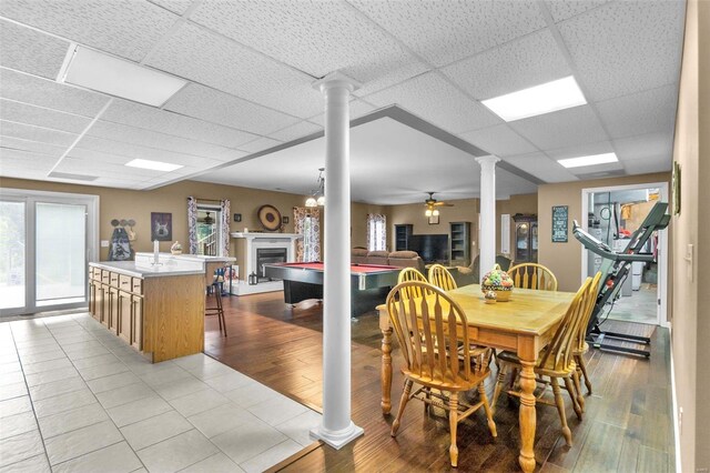 dining room with ceiling fan, hardwood / wood-style floors, a paneled ceiling, and ornate columns