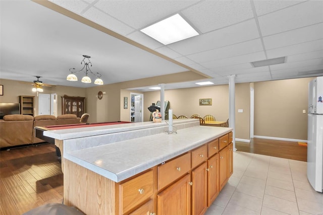 kitchen featuring a center island, a paneled ceiling, and light tile patterned floors