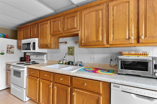 kitchen featuring brown cabinets, white appliances, light countertops, and a sink