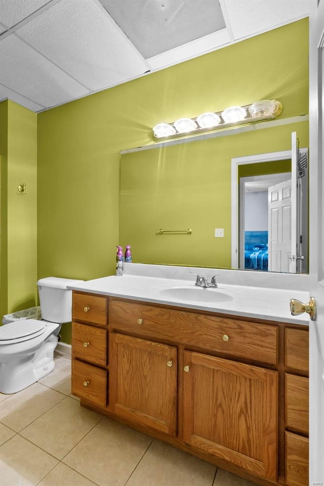 bathroom featuring tile patterned floors, vanity, a paneled ceiling, and toilet