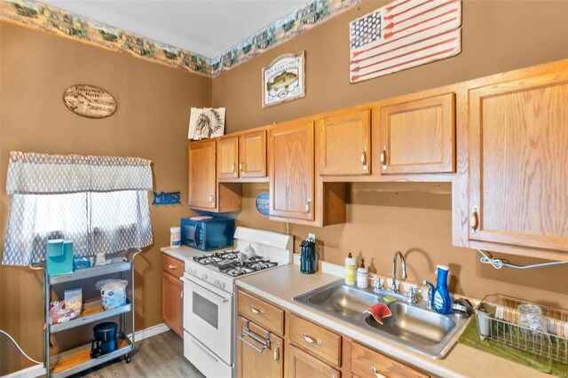 kitchen with white gas stove, sink, and light hardwood / wood-style flooring