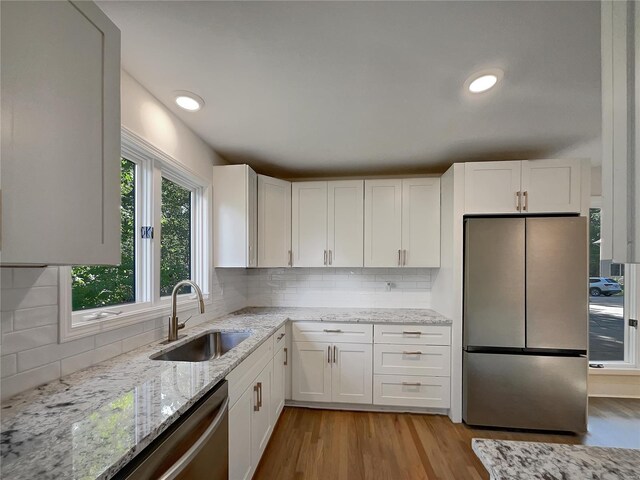 kitchen with tasteful backsplash, plenty of natural light, light hardwood / wood-style flooring, and appliances with stainless steel finishes