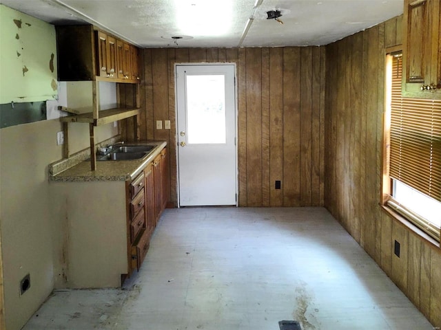 kitchen with light countertops, brown cabinets, a sink, and wooden walls