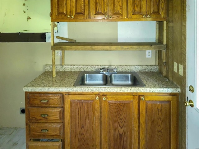 kitchen featuring light countertops, a sink, and brown cabinets