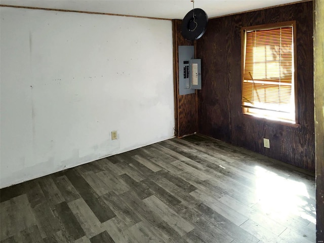 spare room with electric panel, wooden walls, and dark wood-style flooring