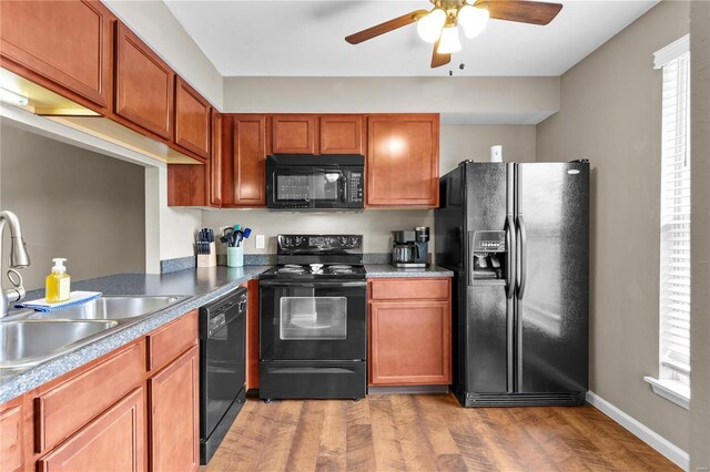 kitchen with black appliances, ceiling fan, sink, and wood-type flooring