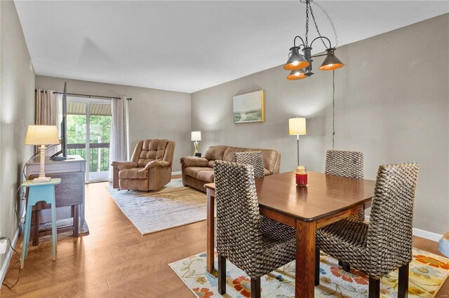 dining space with light wood-type flooring and a notable chandelier