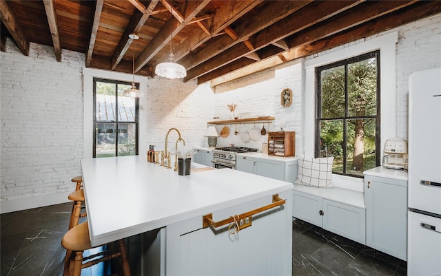 kitchen with brick wall, a kitchen breakfast bar, hanging light fixtures, high end stove, and sink