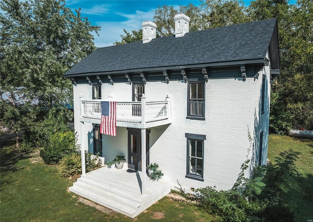 rear view of property with a balcony and a lawn