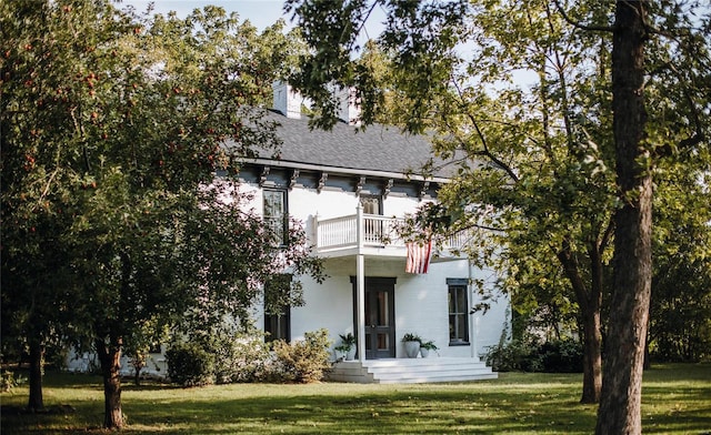 back of house with a lawn and a balcony