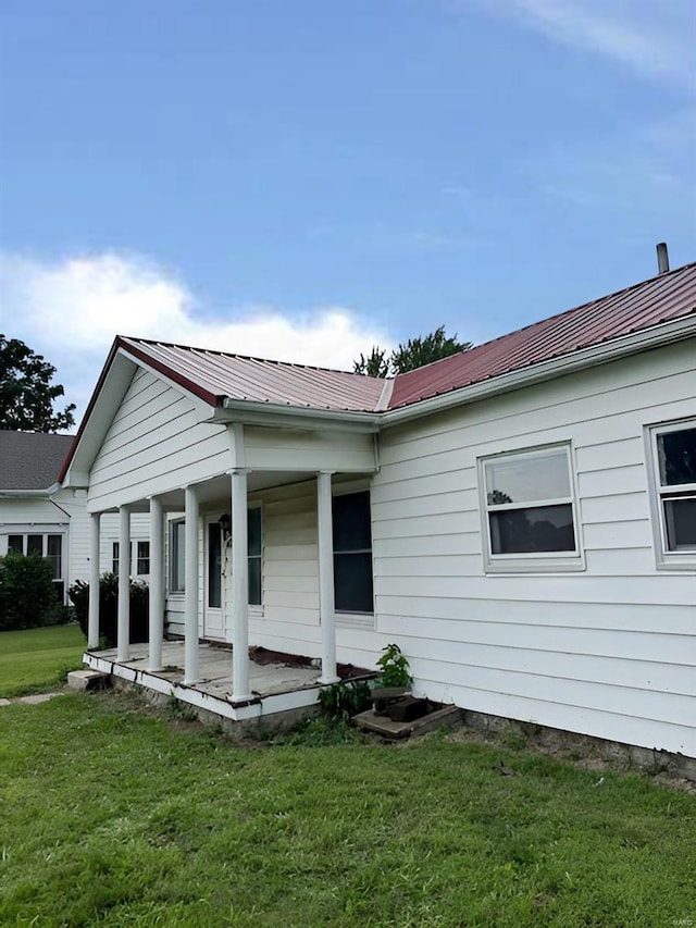 exterior space featuring a front yard, covered porch, and metal roof