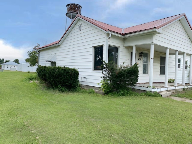 view of front facade featuring metal roof, a porch, and a front lawn