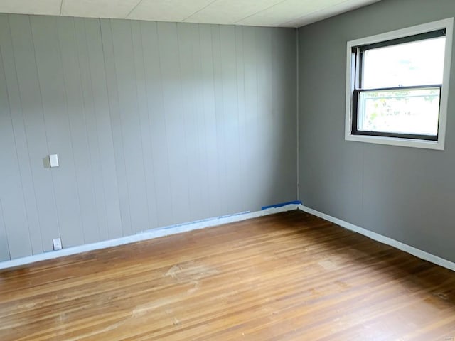 spare room with baseboards and light wood-style floors