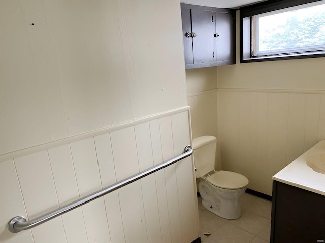 half bath featuring toilet, wainscoting, tile patterned floors, and vanity