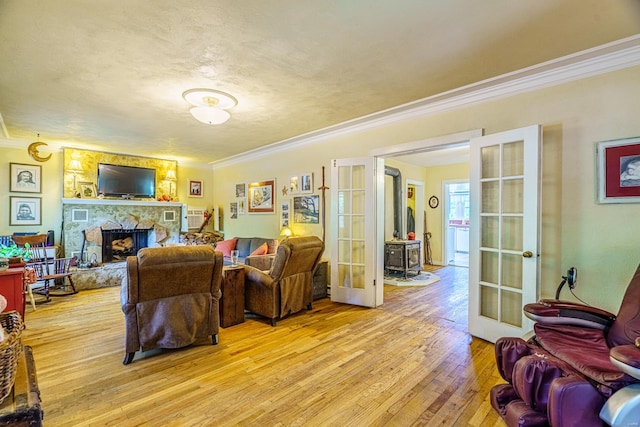 living room with hardwood / wood-style flooring, a fireplace, ornamental molding, and french doors