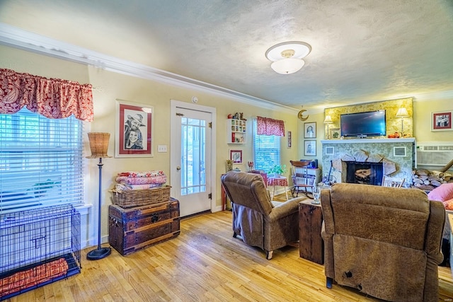 living room with ornamental molding, a stone fireplace, and hardwood / wood-style flooring