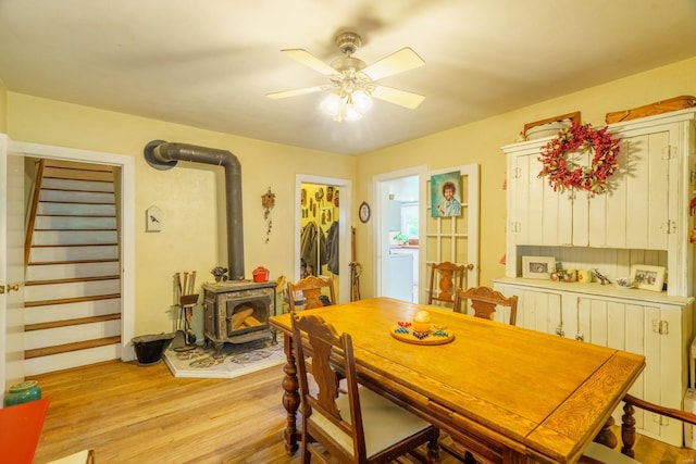 dining room featuring light wood-type flooring, ceiling fan, and a wood stove