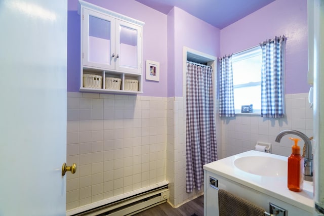 bathroom featuring hardwood / wood-style floors, vanity, curtained shower, a baseboard heating unit, and tile walls