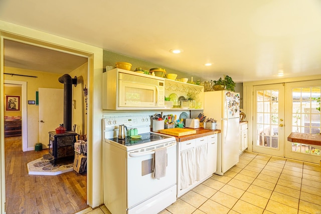 kitchen featuring french doors, white appliances, light hardwood / wood-style flooring, and a wood stove