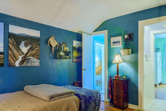 bedroom with lofted ceiling and light wood-type flooring