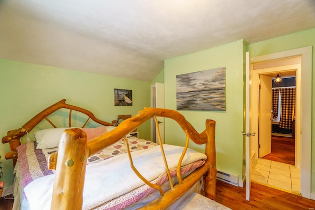 bedroom featuring a baseboard heating unit and wood-type flooring