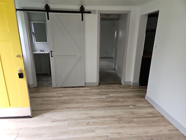 unfurnished room featuring light hardwood / wood-style floors, a barn door, and sink