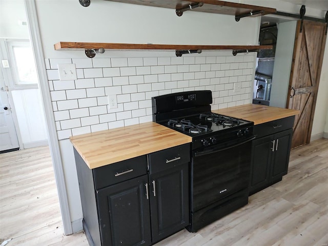 kitchen featuring light hardwood / wood-style flooring, gas stove, butcher block counters, and a barn door